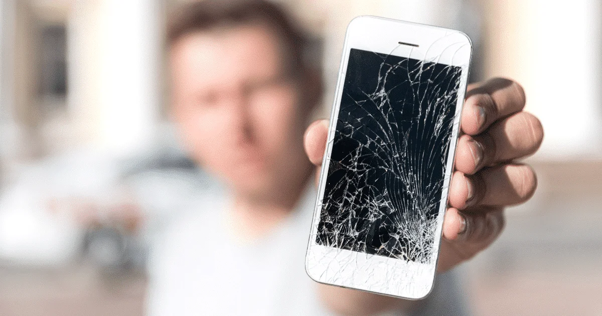 Teléfono móvil roto con pantalla agrietada mostrando pérdida de datos