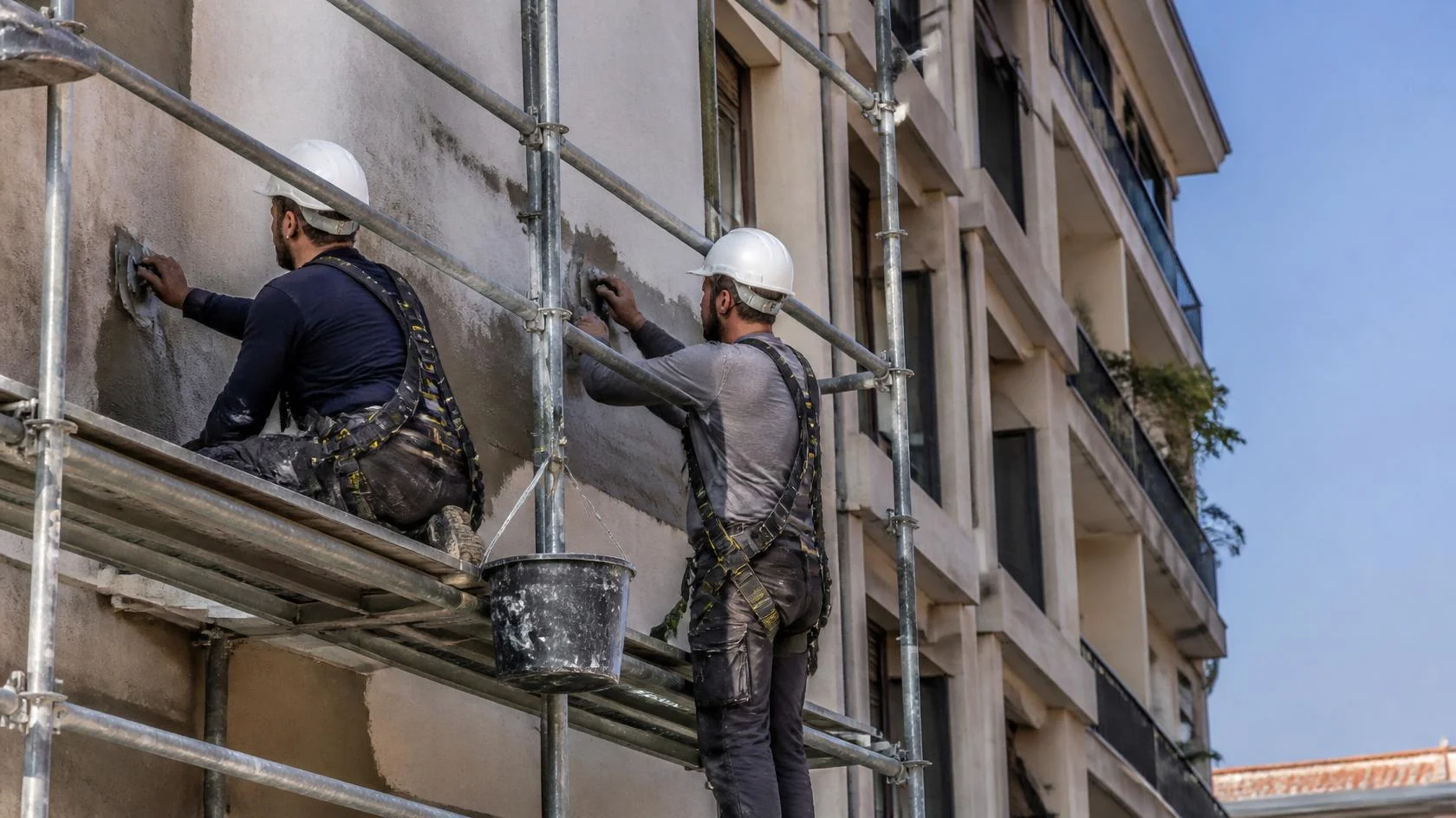 Operarios en andamio reparando y consolidando una fachada tras un desprendimiento
